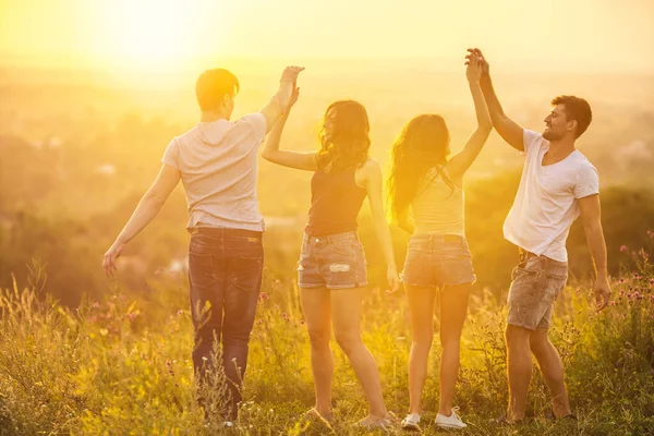 Gündoğumunun arka planında eğlenen dört kişi