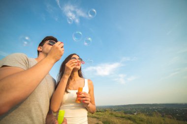 Çift mavi gökyüzünün arka planında kabarcıklar çıkarıyor.