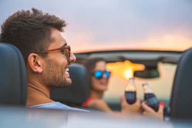 Yakışıklı adam arkadaşlarıyla arabada oturuyor.