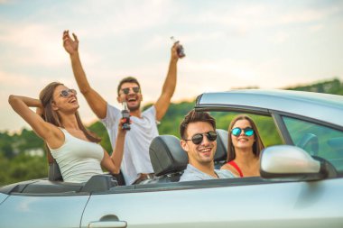 Güneş gözlüklü dört mutlu insan bir Cabrio 'da oturuyor.