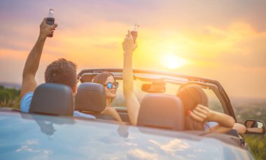 Mutlu insanlar parlak güneş arka planında bir Cabrio 'da otururlar.