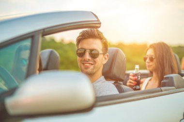 Güneşli arka planda arkadaşları olan bir Cabrio kullanıyor.