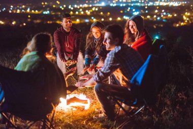 İnsanların şenlik ateşinin yanında el ele tutuşmaları. Gece vakti.