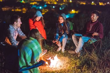 İnsanların şenlik ateşinin yanında el ele tutuşmaları. Gece vakti.