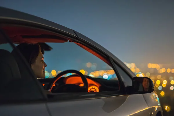 Vrouw Zit Een Auto Achtergrond Van Het Stadslicht Avond Nacht — Stockfoto