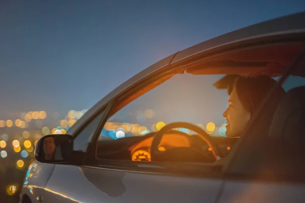 Gelukkige Vrouw Zit Een Auto Lichte Achtergrond Van Stad Avond — Stockfoto