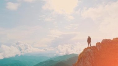 Genç adam dağ yamacında duruyor.