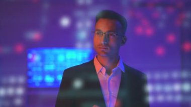 Gözlüklü iş adamı karanlık bir odada hologramın arka planında çalışıyor.