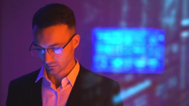 Karanlık odada hologram arka planında çalışan gözlüklü iş adamı.