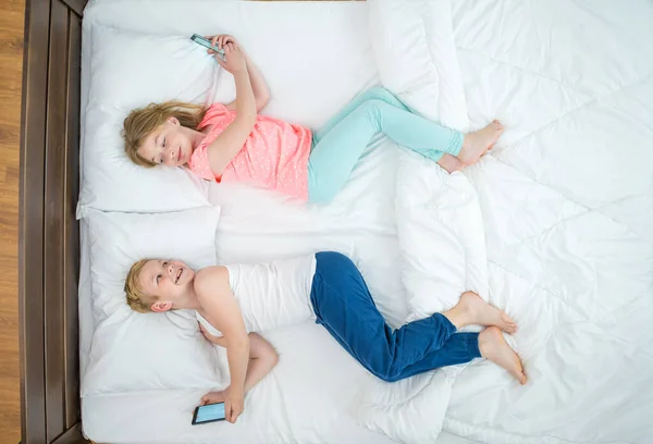 The boy and girl with phones lay on the bed. view from above