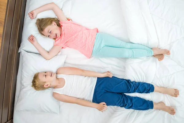 The smile boy and girl lay on the bed. view from above