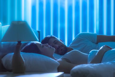 Yataktaki adamın yanında uyuyan tatlı kadın. Gece vakti.