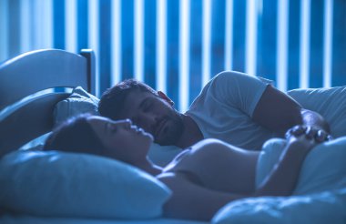 Genç çift rahat yatakta uyuyor. Gece vakti.