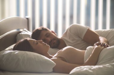Genç çift rahat bir yatakta uyuyor.