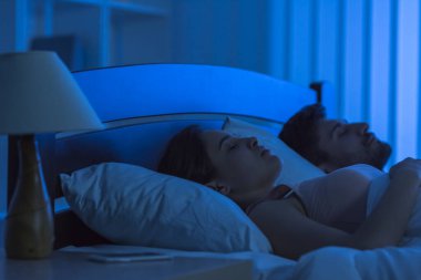 Yatakta uyuyan genç çift. Gece vakti.