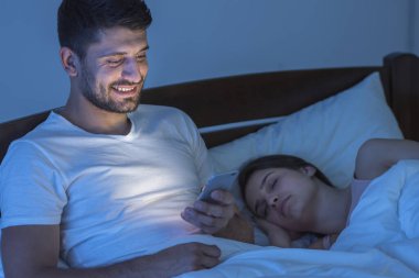 Uyuyan kadının yanındaki erkek telefonu. Gece vakti.