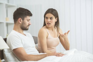 Yataktaki adamın yanında öfkeli kadın hareketi.