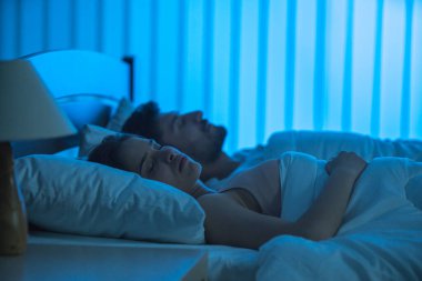 Yatakta uyuyan genç çift. Gece vakti.