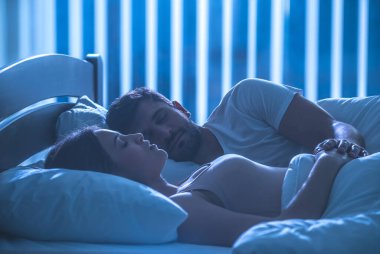 Bir yatakta uyuyan ve el ele tutuşan adam ve kadın. Gece vakti, tüm dikkatini topla.