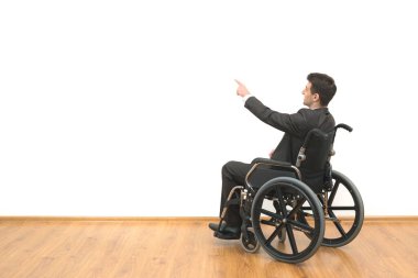 Tekerlekli sandalyedeki engelliler beyaz duvar arkasında el kol hareketi yapıyorlar.