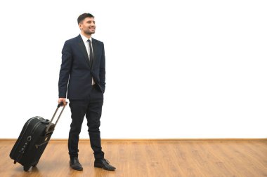 Beyaz duvar arkasında duran çantalı iş adamı.