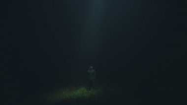 UFO, karanlık arka plandaki bir adama parlak bir ışık tutar.