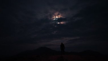 Karanlık arka plandaki adamın üstündeki UFO uçuşu.