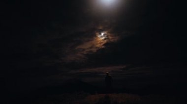 Karanlık arka planda bir adamın üstündeki UFO uçuşu.