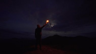 Gece dağında elinde havai fişek sopası olan adam.