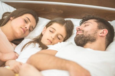 Aile yatakta uyuyor.