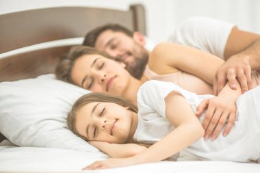 Kızı ve ailesi yatakta uyuyor.