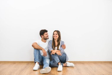 Mutlu çift beyaz duvarın yanında oturuyor.