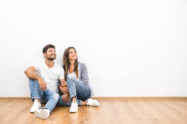 Mutlu çift beyaz duvarın arkasında oturuyor.