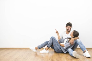 Gülümseme çift oturmak ve beyaz duvar arka plan üzerinde jest