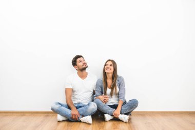 Adam ve kadın boş duvarın yanında oturuyor.