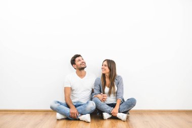 Neşeli adam ve kadın boş duvarın yanında oturuyor.