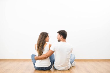 Mutlu çift beyaz duvarın arkasında oturuyor.