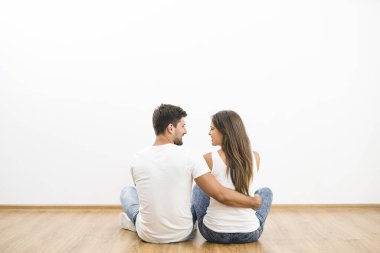 Mutlu çift beyaz duvarın arkasında oturuyor.