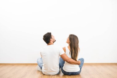 Mutlu çift oturur ve beyaz duvara bakar.