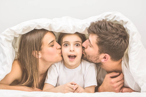 The parents kissing their daughter