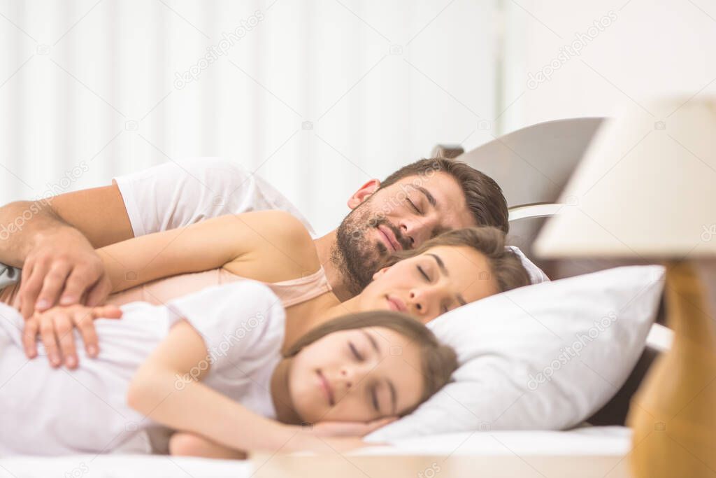 The happy family sleeping on the comfortable bed