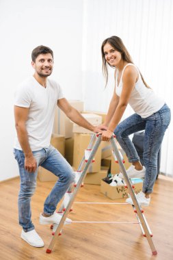 Mutlu çift karton kutuların arkasındaki merdivende duruyor.