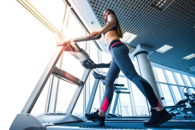 Panoramik pencerenin arkasında koşu bandında koşan kadın.