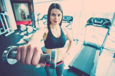 Kadın spor salonunda bir dambıl tutuyor. Kapat.