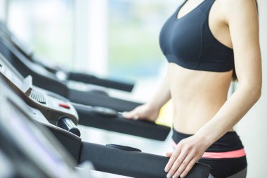 Spor salonundaki koşu pistindeki atletik kadın