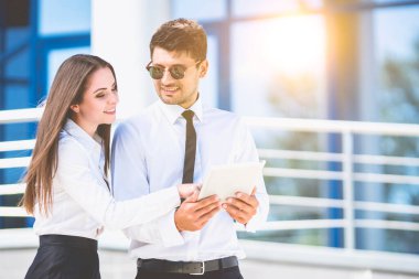 Kadın ve erkek, iş merkezinin arka planında bir tabletle duruyorlar.