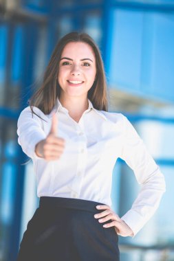 Gülümseyen kadın iş merkezinin arka planında başparmağını kaldırıyor.