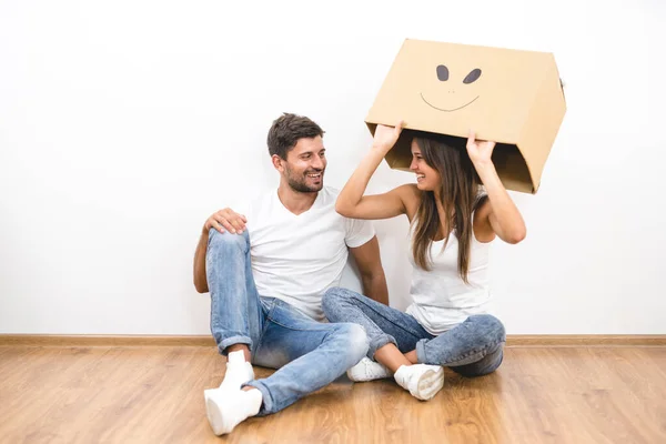 这对幸福的夫妇带着一个纸盒坐在地板上 — 图库照片