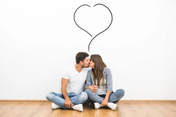 这对接吻的夫妇坐在墙上的爱情符号旁边 — 图库照片