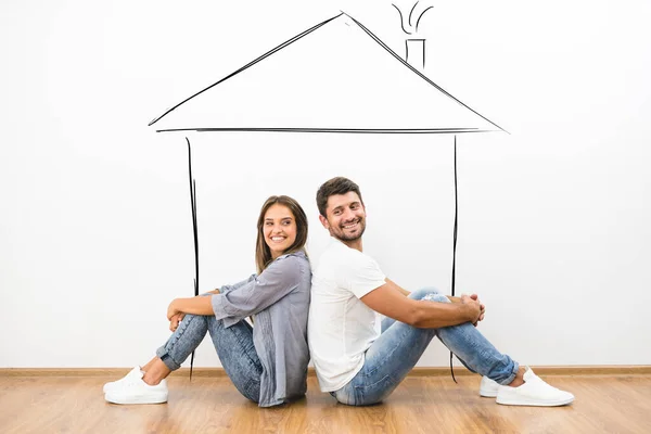 The couple sit on the floor near a house illustration on the wall